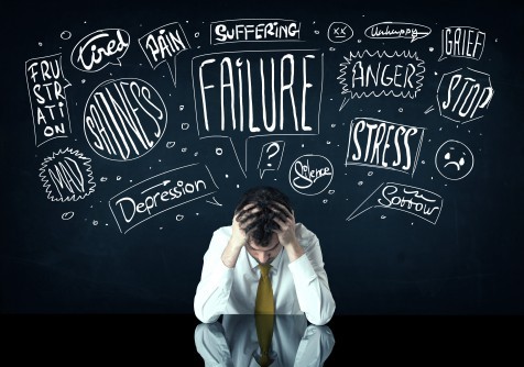 Depressed businessman sitting under trouble thought boxes