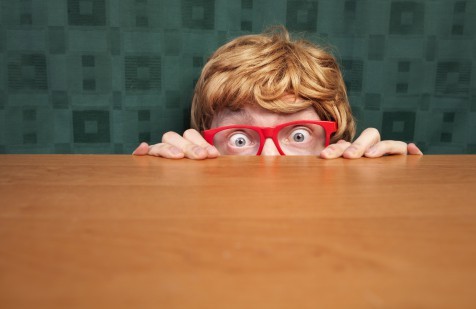 Scared nerd hiding behind a desk