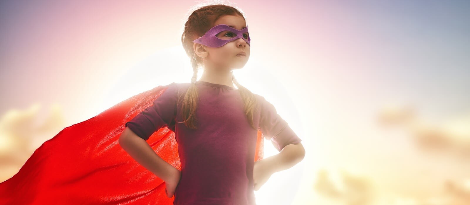 Little child girl plays superhero. Child on the background of su